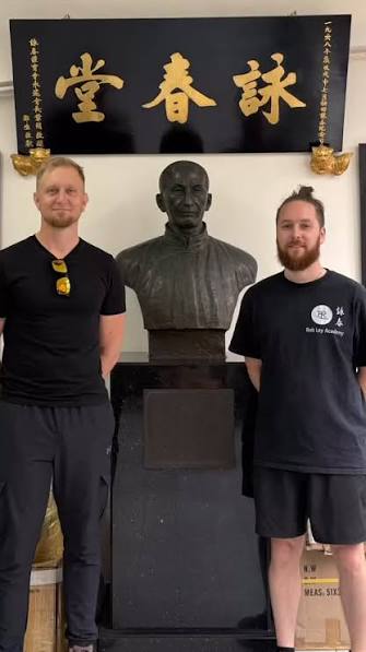 Cédric Farcy aux côtés de Sifu Rob Ley devant le buste d’Ip Man